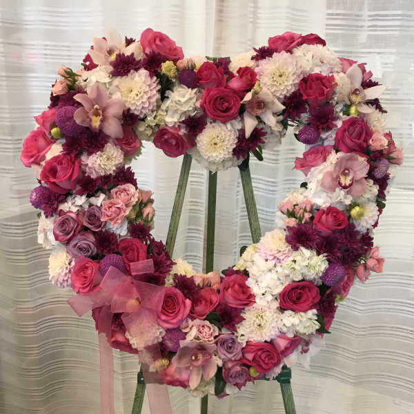 Heart-shaped floral wreath with pink and white flowers on an easel