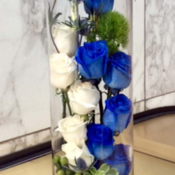 Tall glass vase with white and blue roses and small accent flowers