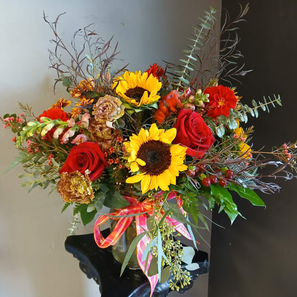 Bouquet of red roses and sunflowers in a glass vase with a ribbon