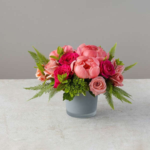 Pink and coral flowers arranged in a gray vase