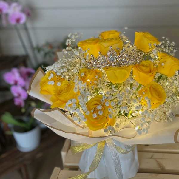 Yellow roses with baby's breath and a jeweled tiara in wrapped bouquet