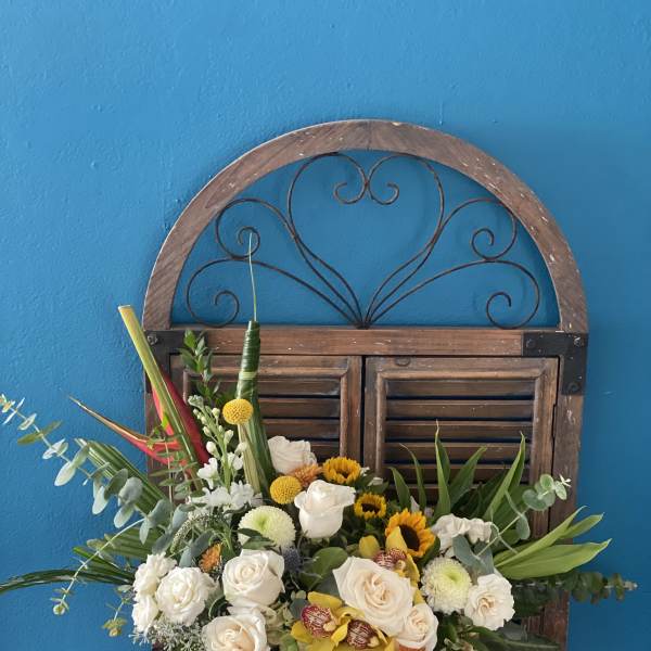 White roses and sunflowers in a white vase with greenery