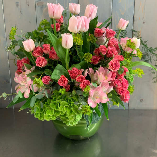 Pink tulips and roses arranged in a green vase