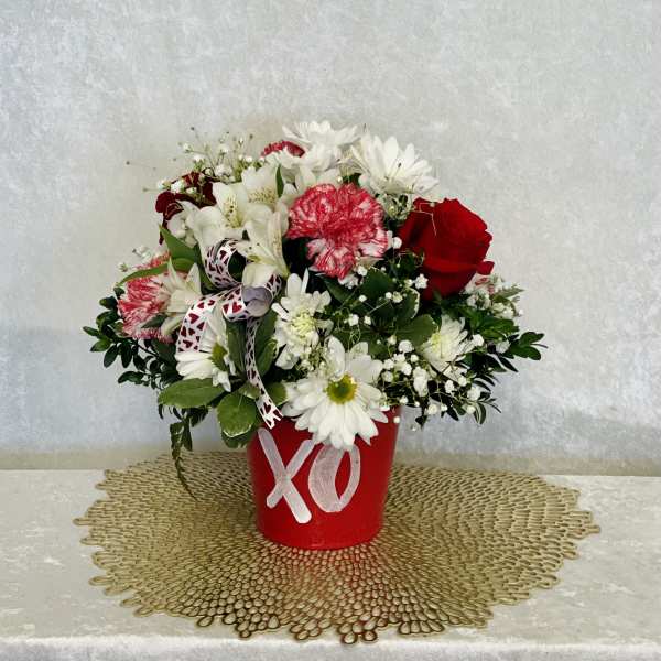 Red bucket of mixed flowers with an XO decoration
