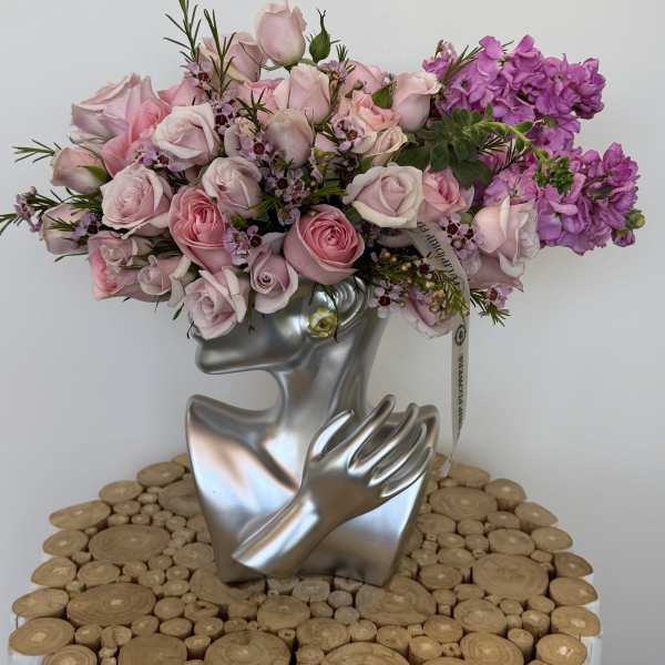 Pink and purple rose bouquet in a silver face-shaped vase