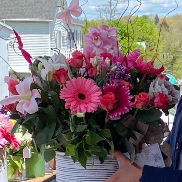 Pink and white mixed flower arrangement in a striped container