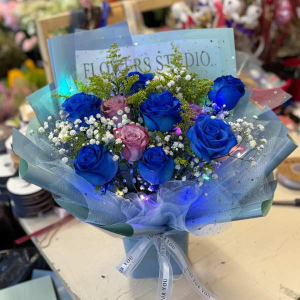 Bouquet of blue and pink roses with baby's breath in blue wrap