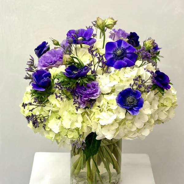 Purple and white flower arrangement in a clear glass vase