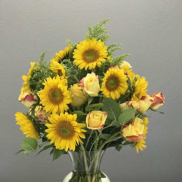 Sunflower and yellow rose bouquet in a clear glass vase