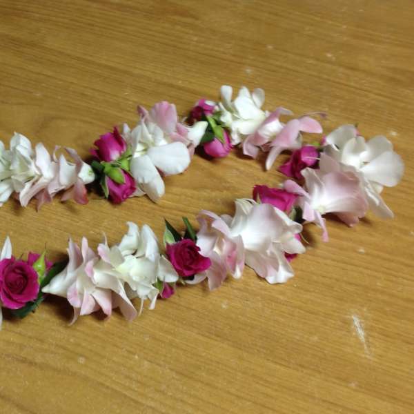 Two floral garlands of pink and white blossoms on a wooden surface