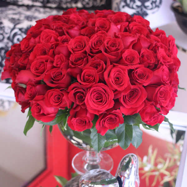 Large dome of red roses arranged in a clear glass pedestal vase