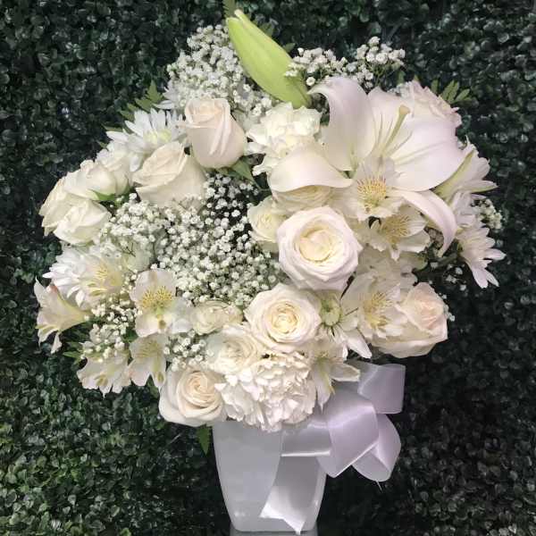 White rose and lily bouquet with baby's breath in a white vase