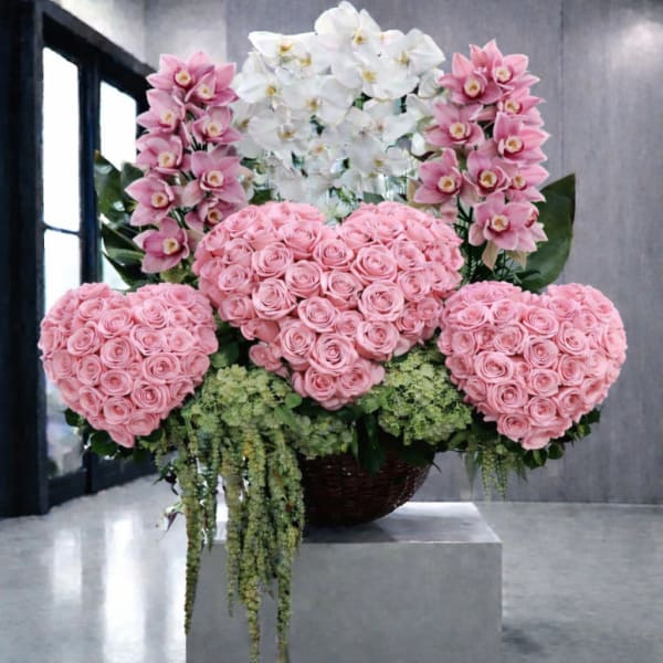 Pink rose heart arrangement with white and pink orchids in a basket