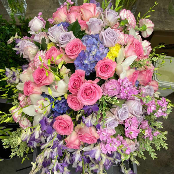 Large bouquet of pink and lavender roses with purple orchids and blue hydrangea