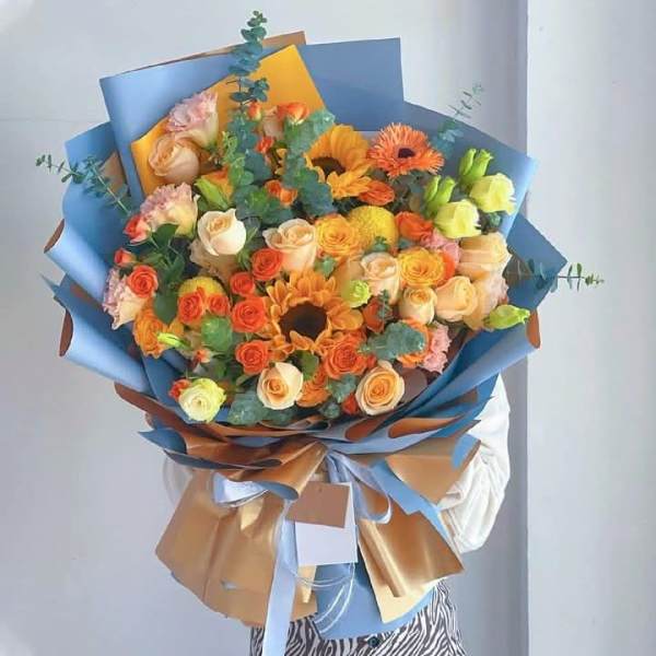 Large bouquet of orange and peach roses with sunflowers and gerbera daisies