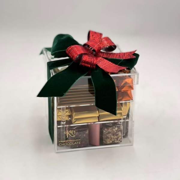 Clear gift box of assorted chocolates tied with a red and green ribbon