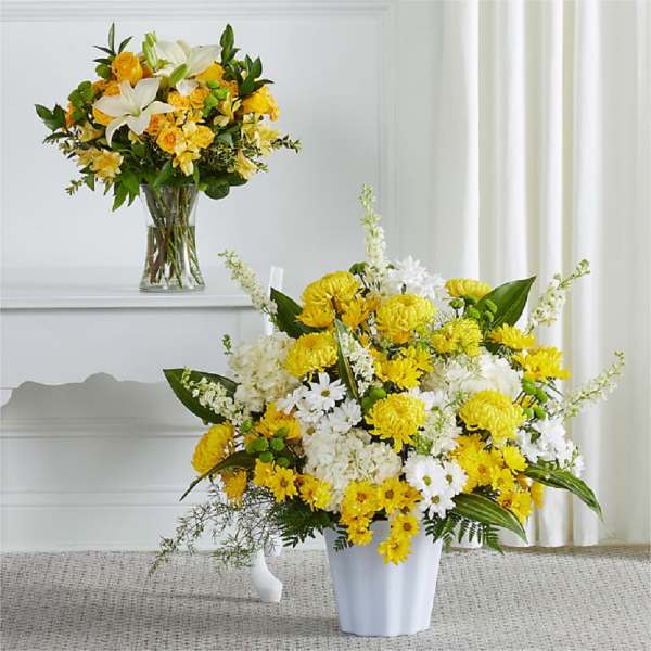 Yellow and white flower arrangements in a vase and white container