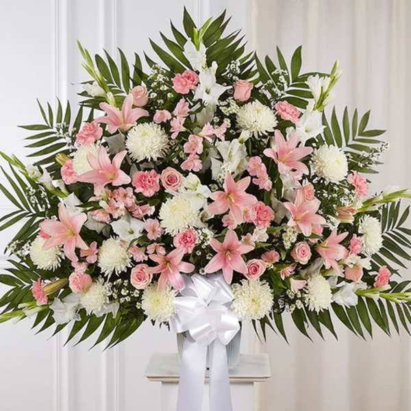 Large pink and white floral spray in a vase with a white ribbon