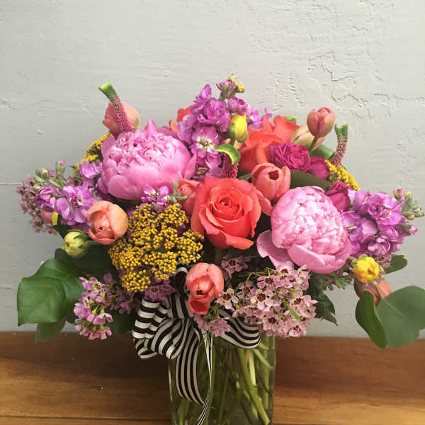 Colorful mixed bouquet in a glass vase with a striped ribbon
