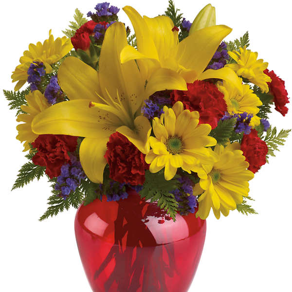 Yellow lilies and daisies in a red glass vase