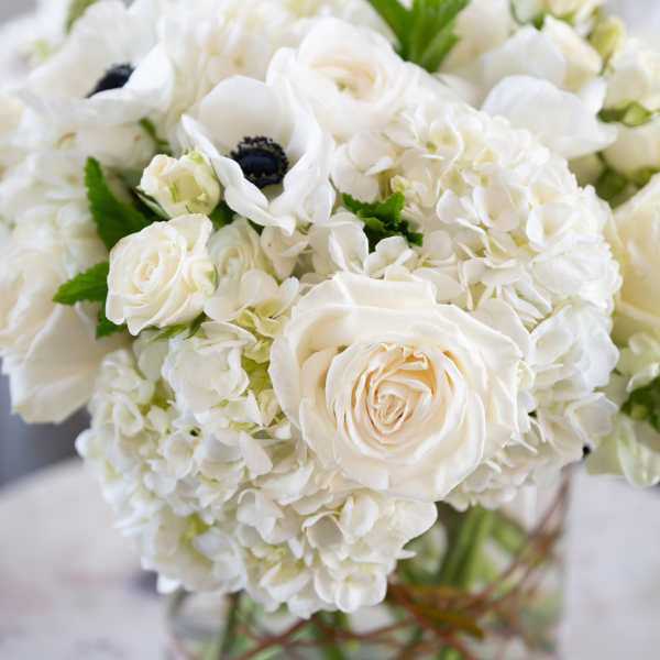 White roses and hydrangeas arranged in a clear glass vase.