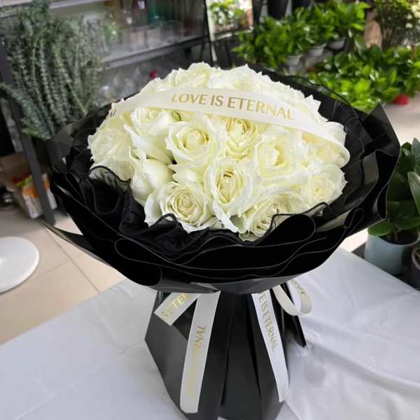 White rose bouquet wrapped in black paper with a ribbon