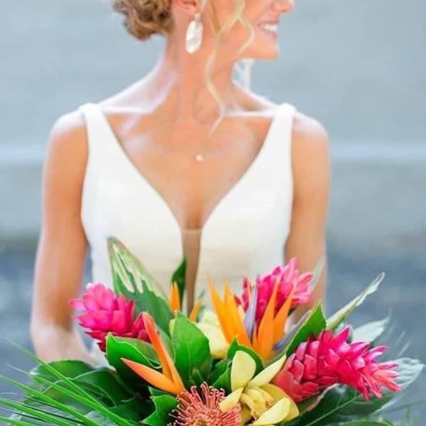 Bride holding a tropical bouquet with pink, orange, and yellow flowers
