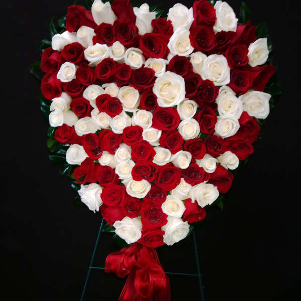Heart-shaped arrangement of red and white roses with a red ribbon