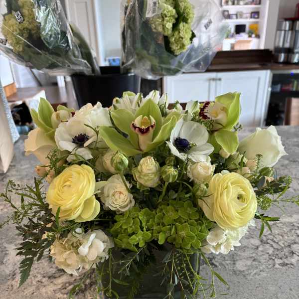 Cream and green floral arrangement in a square glass vase
