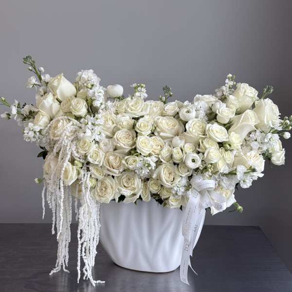 White roses and calla lilies arranged in a white vase