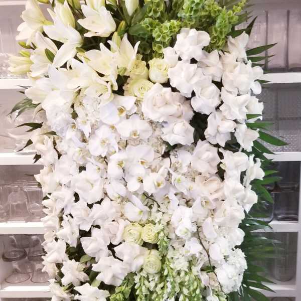 Tall white floral standing spray on an easel with green accents