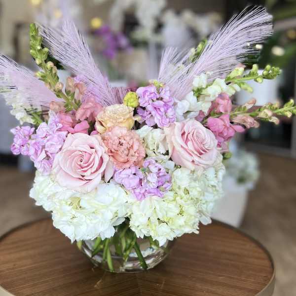 Pink roses and pastel flowers arranged in a clear glass vase