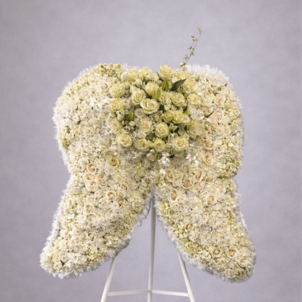 Large standing arrangement of white and cream flowers shaped like angel wings on a white easel.