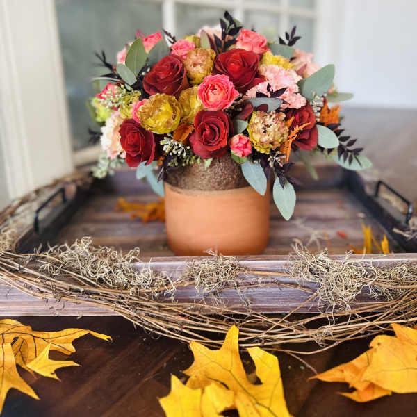 Bouquet of red, pink, and yellow roses in a copper-toned vase