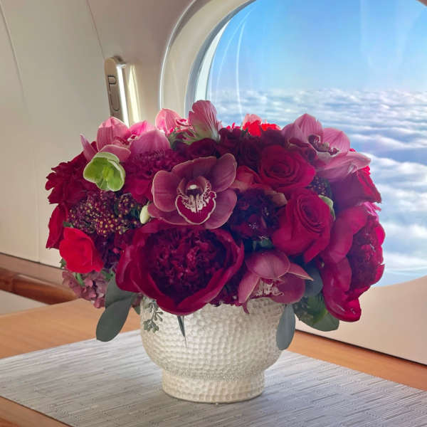 Bouquet of red and pink flowers in a white textured vase