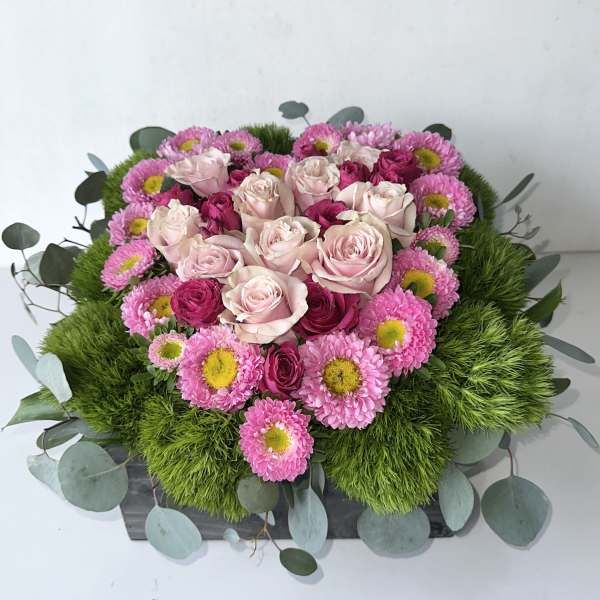 Pink roses and daisies arranged in a low rectangular box