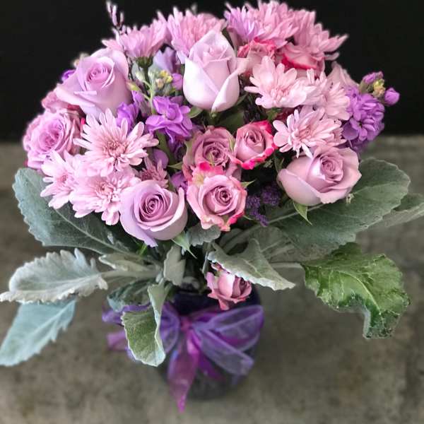 Pink and lavender bouquet of roses and chrysanthemums tied with a purple ribbon