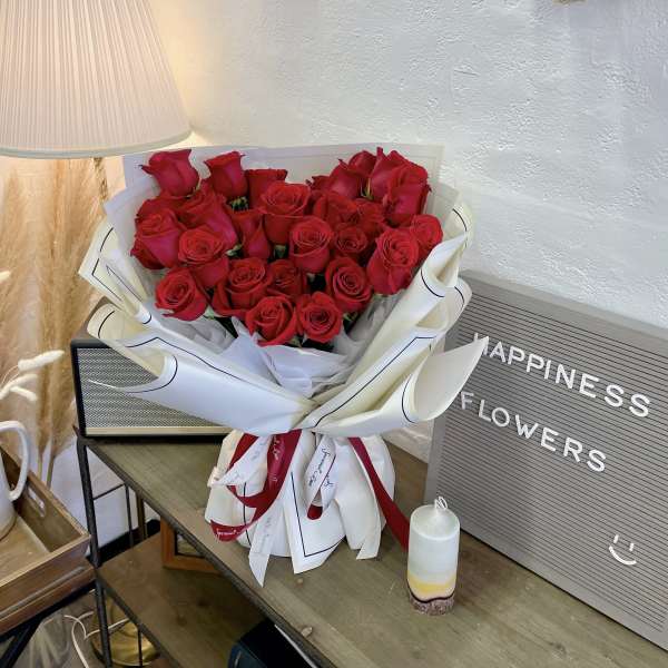 Bouquet of red roses wrapped in white paper with ribbon