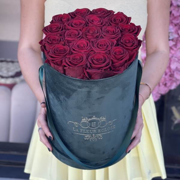 Bouquet of deep pink roses in a teal hatbox