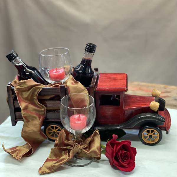 Decorative truck with wine bottles, glass candle holders, and a red rose