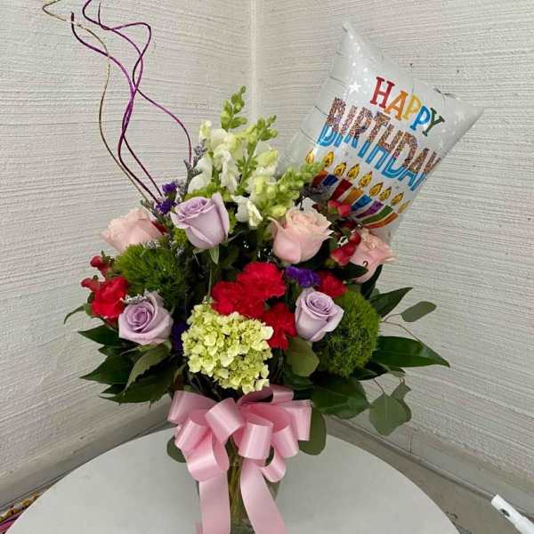 Mixed flower bouquet with a birthday balloon in a glass vase