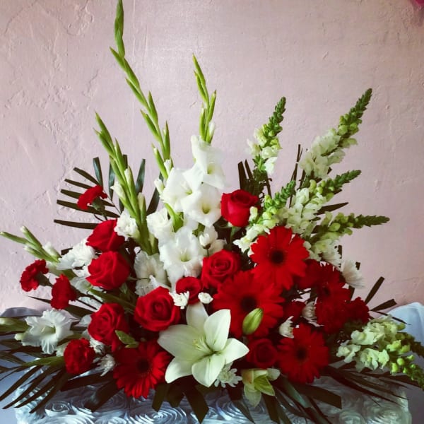 Red and white floral arrangement with roses, lilies, and gerbera daisies