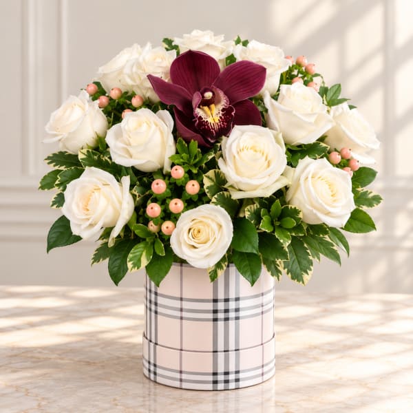White roses and a burgundy orchid in a plaid hatbox arrangement