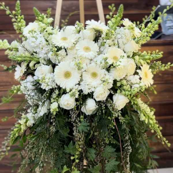 White floral arrangement with daisies and roses on a stand