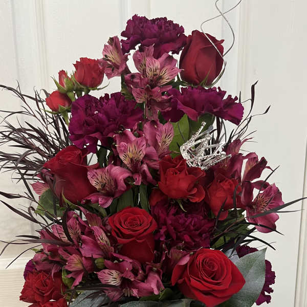 Red roses and pink alstroemeria in a black mug with decorative picks
