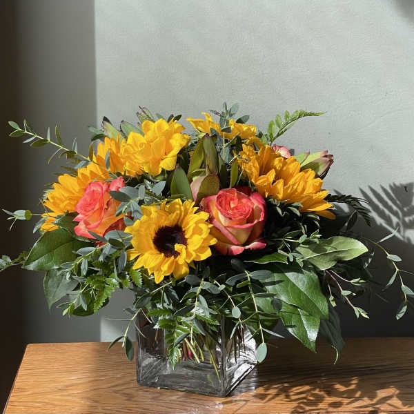 Bouquet of yellow sunflowers and pink roses in a glass vase