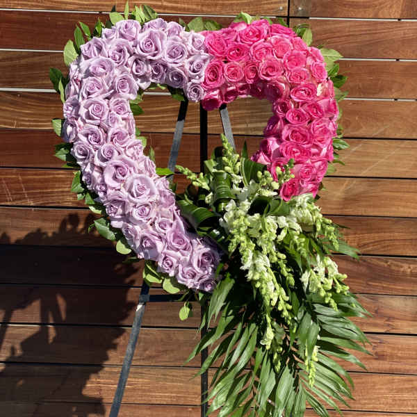 Heart-shaped floral wreath of pink and lavender roses with trailing greenery
