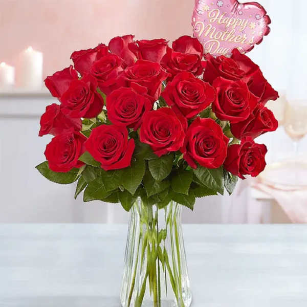Red roses in a clear glass vase with a pink heart balloon