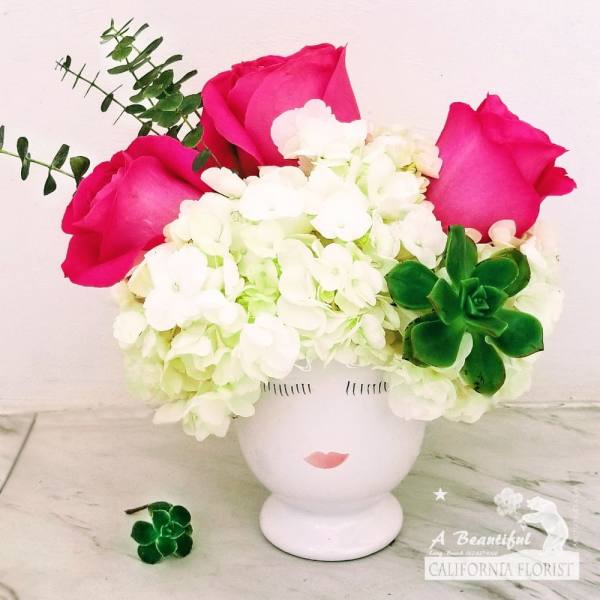 Pink roses and white hydrangeas in a white face vase