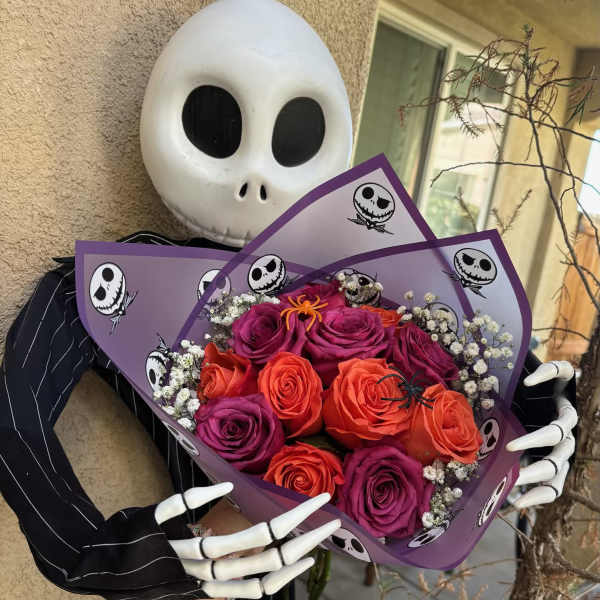 Bouquet of orange and purple roses wrapped in purple paper with skull prints